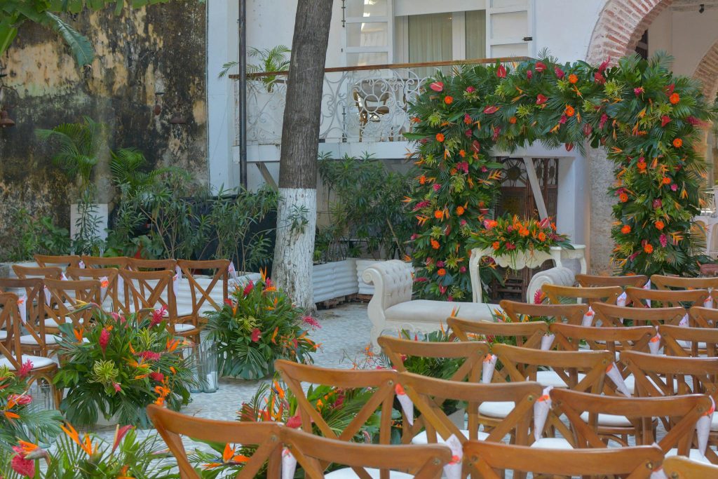 A beautifully decorated outdoor wedding ceremony with a floral arch and elegant seating arrangement.