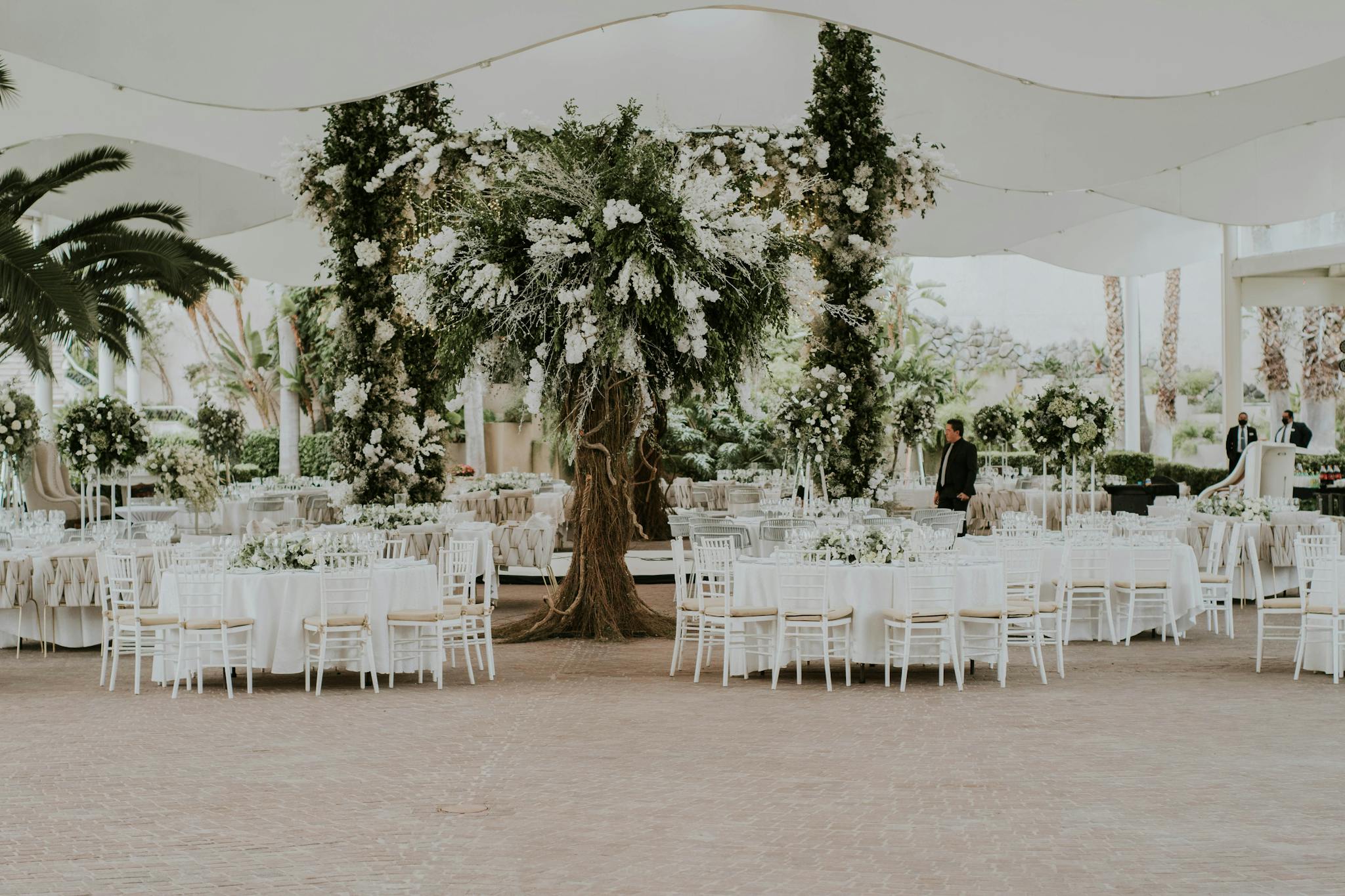 Beautifully decorated outdoor wedding venue with floral arrangements and white tables.
